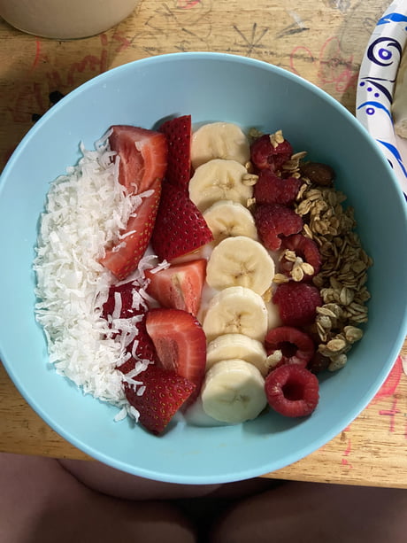 Yogurt bowl with shredded coconut, strawberries, bananas, raspberries and granola