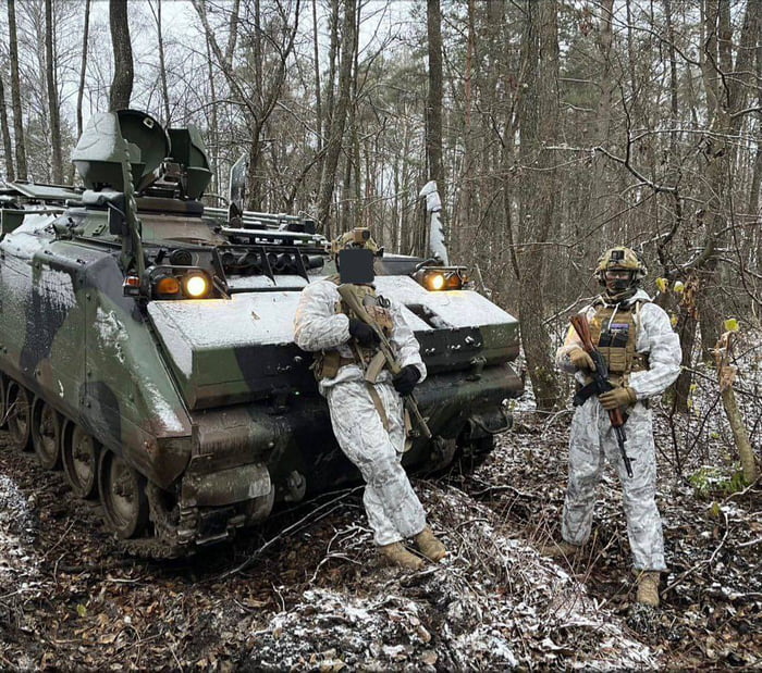 Ukranian soldiers in winter gear standing next to a dutch YPR 765