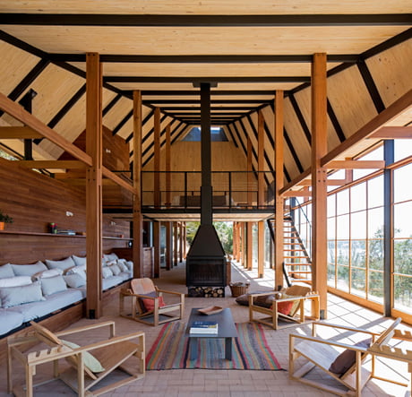 Spacious open plan living spaces with aligned beams and a mezzanine bedroom on the sloping shores of Panguipulli Lake, Chile