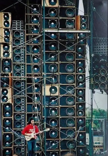 Jerry Garcia in front of the Grateful Dead's “Wall of Sound” in 1974. The  PA system would come to weigh more than 70 tons, and contain hundreds of  amps and speakers that