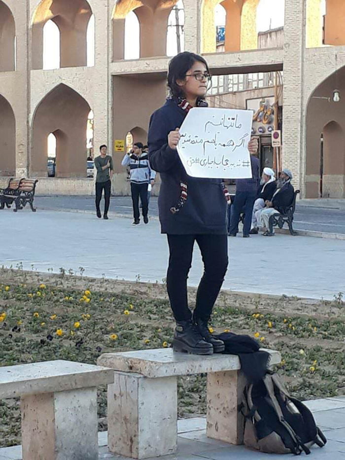 Iranian girl takes off her compulsory hijab and protests against mandatory dress code for women.